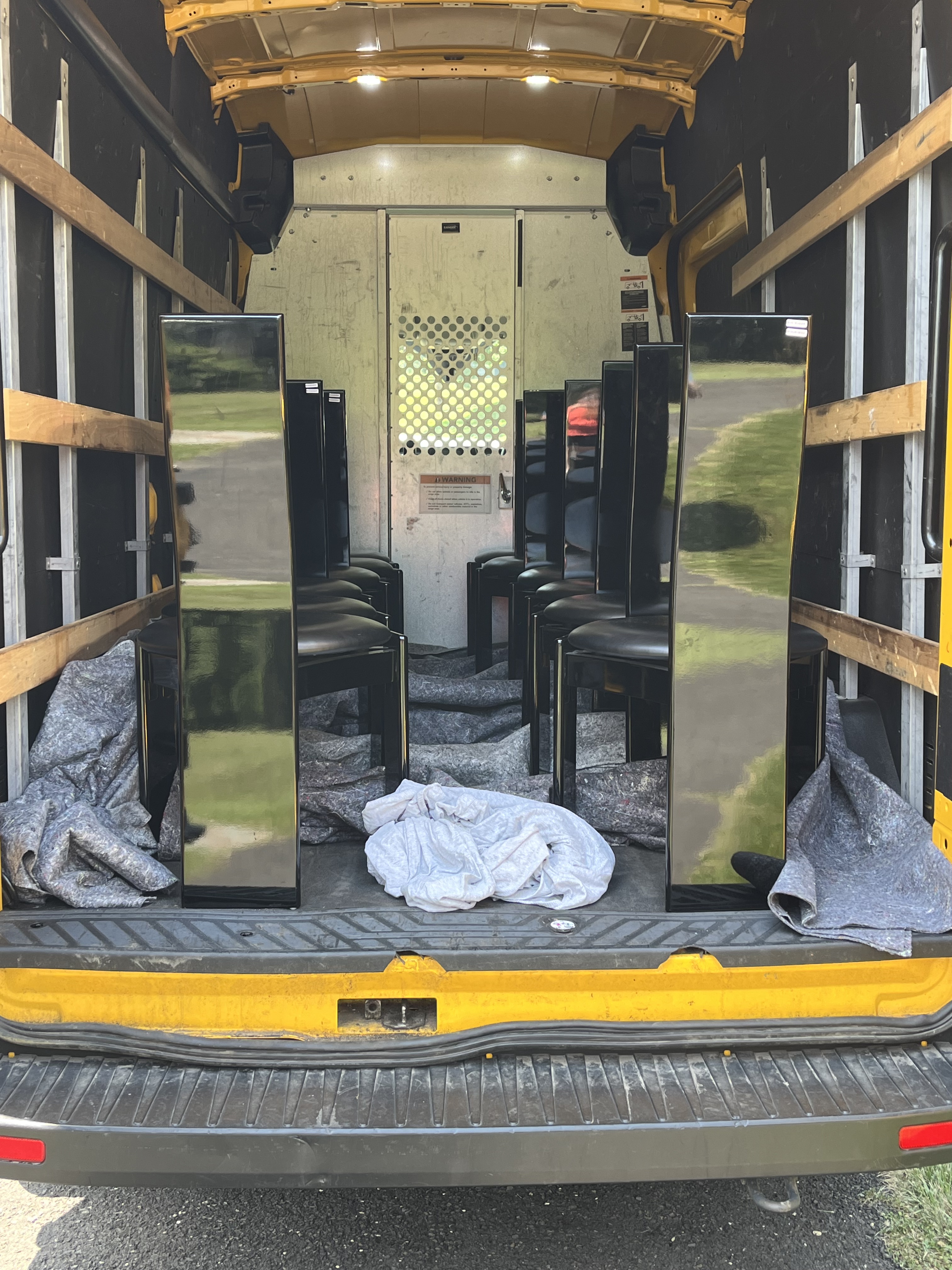 12 modern dining chairs in the back of a cargo van.