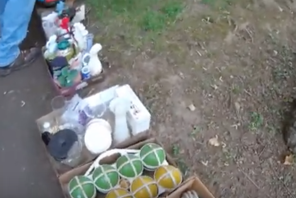 Random box lots on the ground at an estate auction containing random household items, a bocce ball set and other random items.