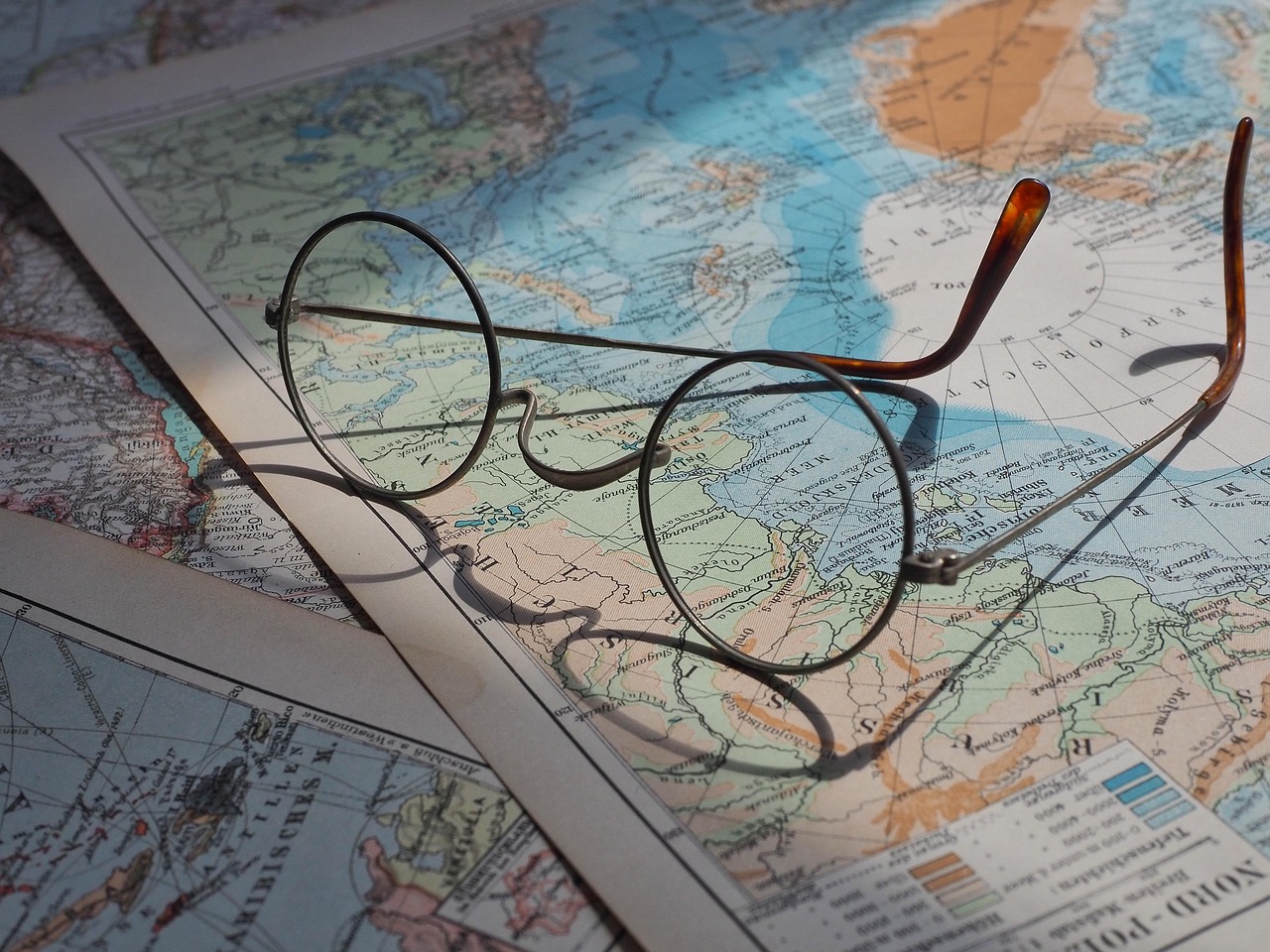 Photo of a pair of old fashioned glasses on top of a map.
