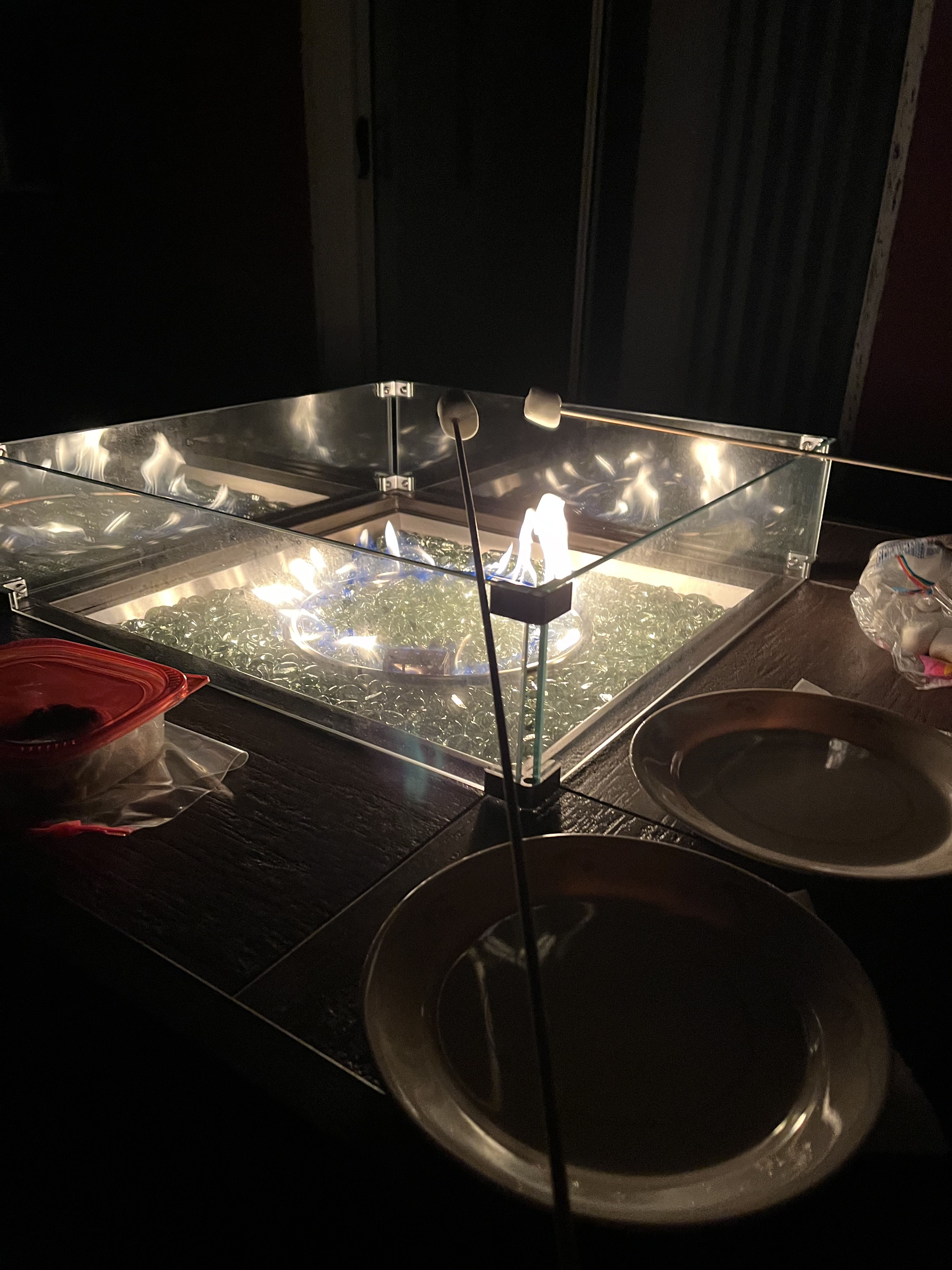 Marshmallows on sticks over a gas firepit.