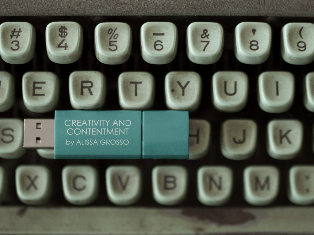 Photo of a vintage typewriter keyboard with a USB stick in turquoise blue resting on the keys. The USB stick reads Creativity and Contentment by Alissa Grosso