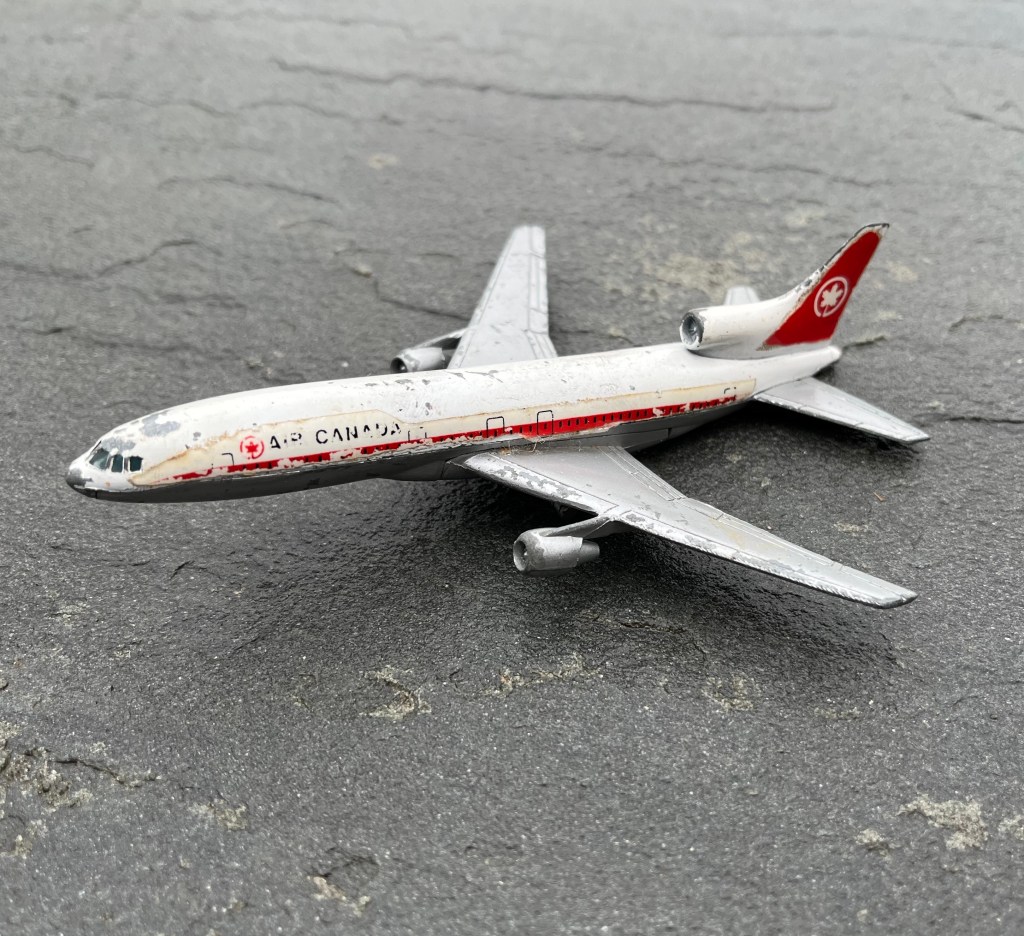 Photo of a battered die cast Air Canada plane resting on dark gray slate.