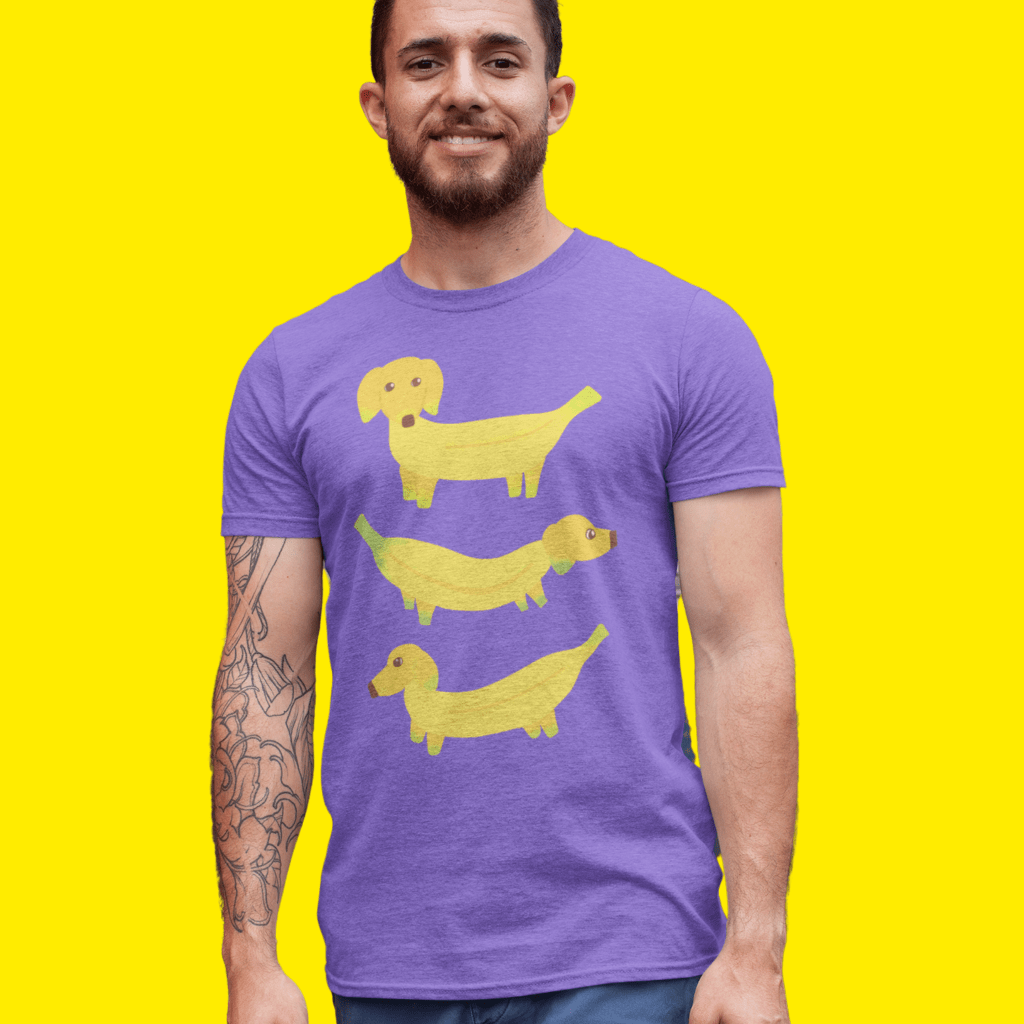Photo of a man wearing a purple t-shirt illustrated with yellow dogs whose bodies are made out of bananas.